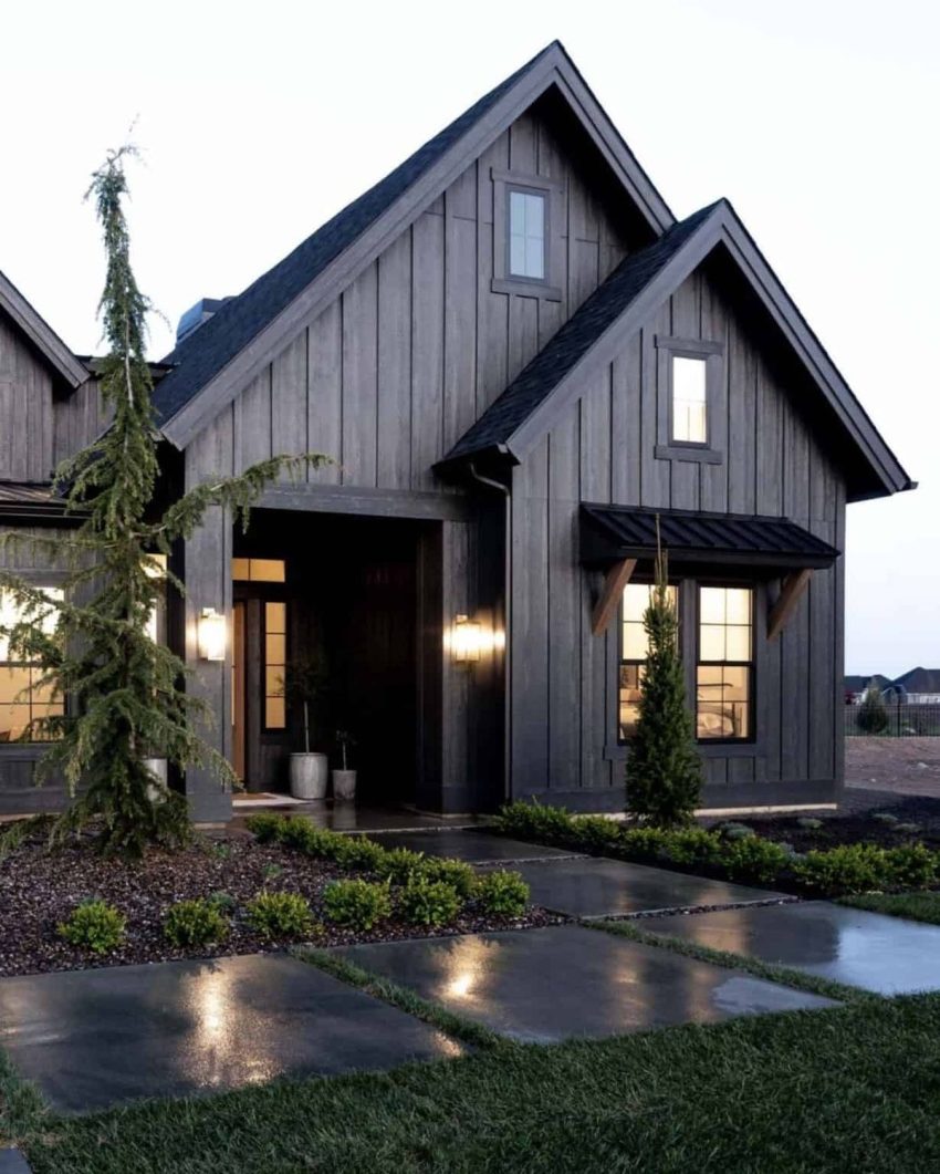 Modern black farmhouse exterior with warm window lighting