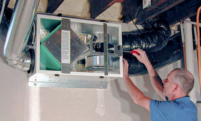 Technician inspecting heat recovery ventilator unit in home basement