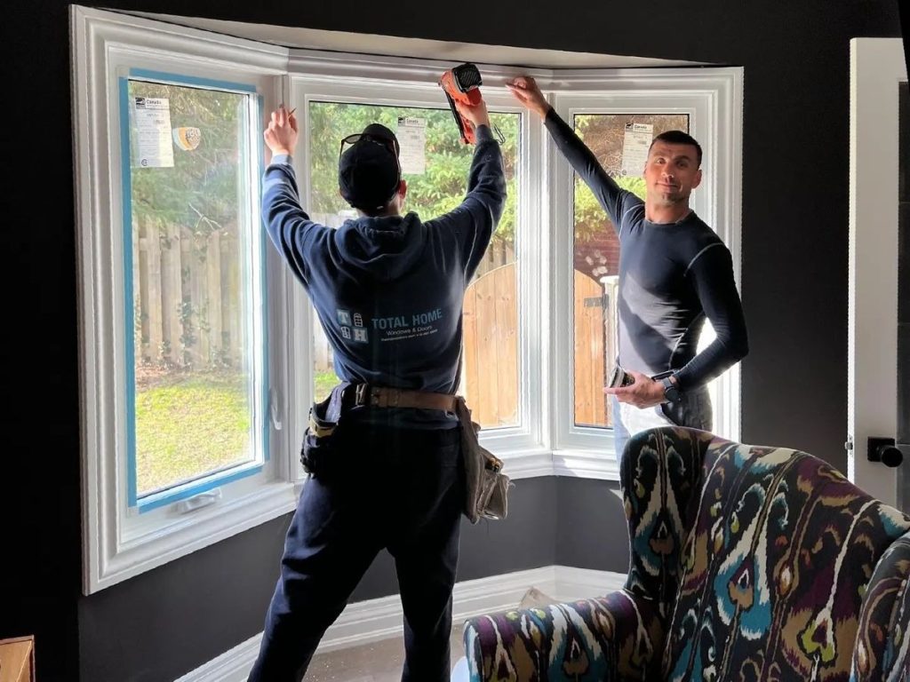 Professional window installers fitting new energy-efficient bay windows